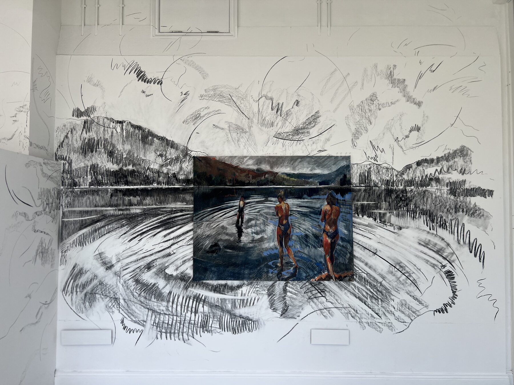 Large scale charcoal wall drawing with a framed painting installed at its centre
